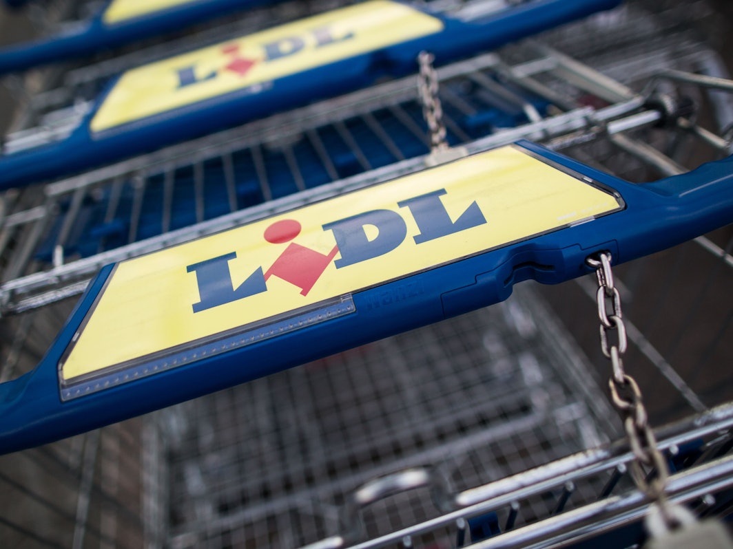 Mehrere Lidl-Einkaufswagen stehen in einer Reihe.