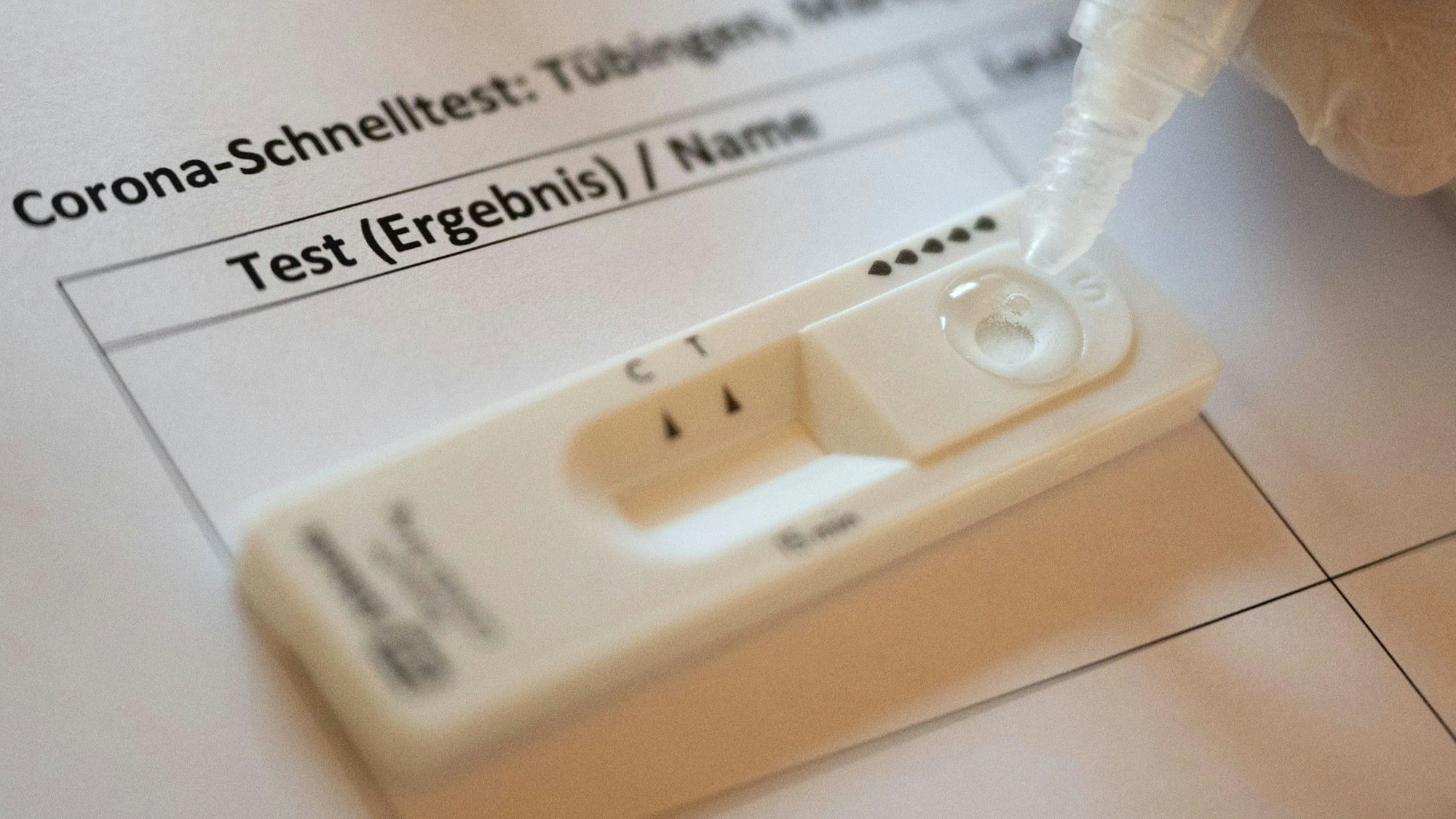 Ein Mitarbeiter einer Corona-Teststation träufelt Sekretlösung in die Kartusche eines Schnelltests.