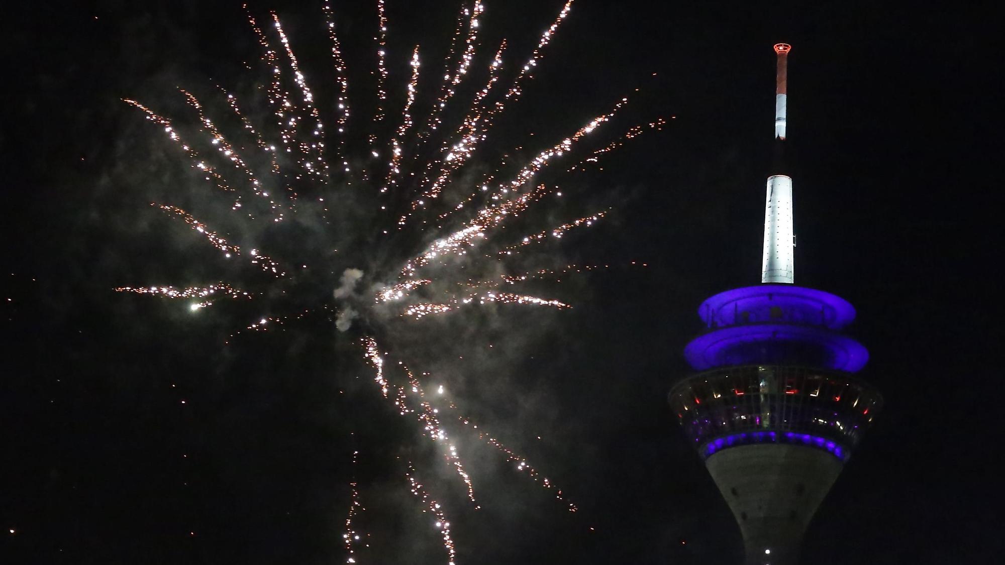 Eine Silvesterrakete explodiert vor dem Düsseldorfer Rheinturm.