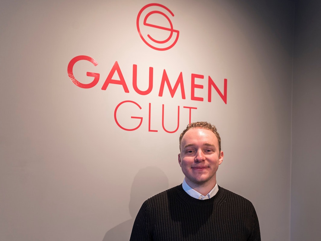 Besitzer Leon Schlichte vor dem Logo seines Restaurants.