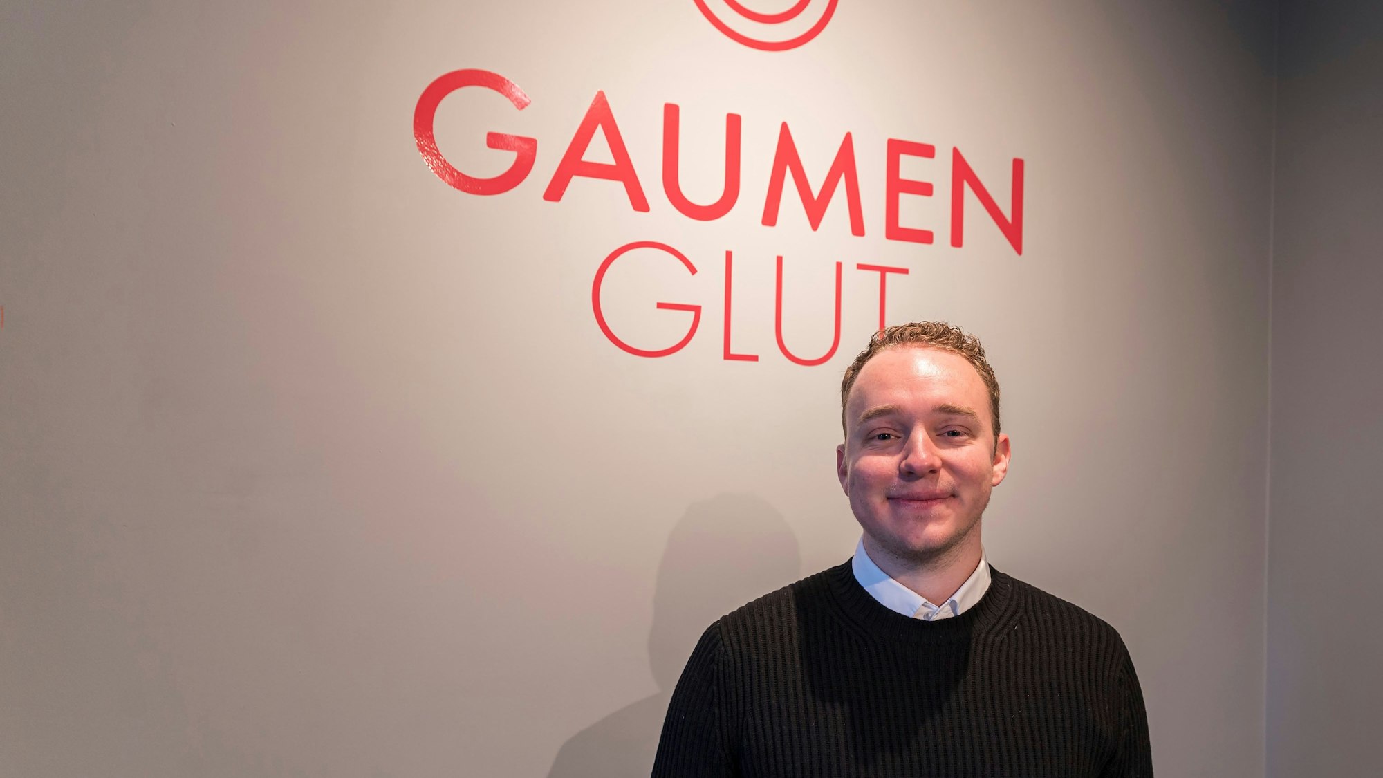 Besitzer Leon Schlichte vor dem Logo seines Restaurants.