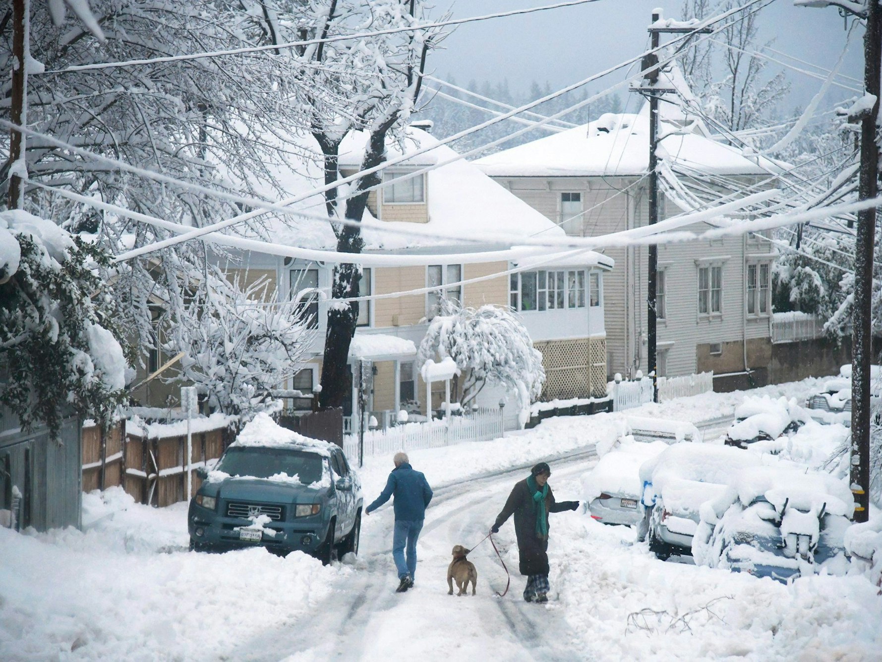 Anwohner laufen am 27. Dezember 2021 mit einem Hund durch den Schnee.