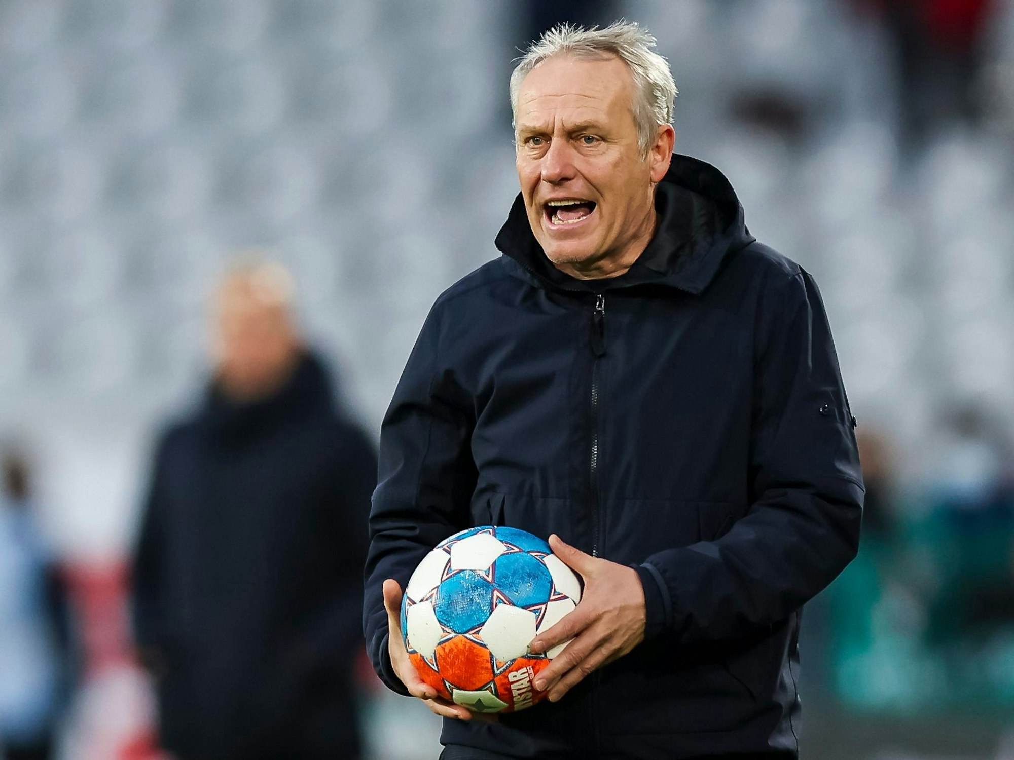 Freiburg-Trainer Christian Streich hält beim Spiel gegen die TSG Hoffenheim den Ball in der Hand.
