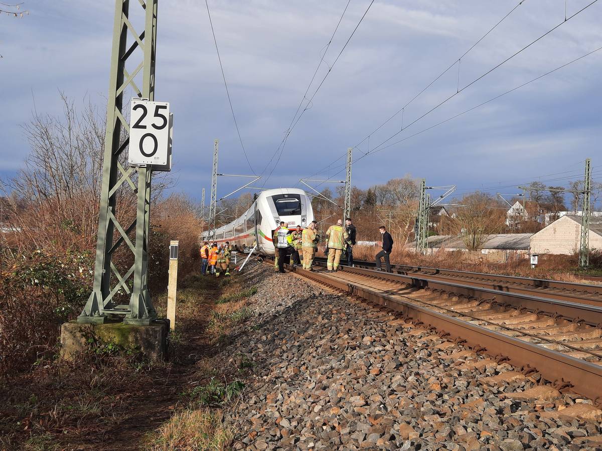 Ein ICE steht auf den Gleisen, davor und daneben Experten der Deutschen Bahn, die sich den Schaden an der Oberleitung angucken.