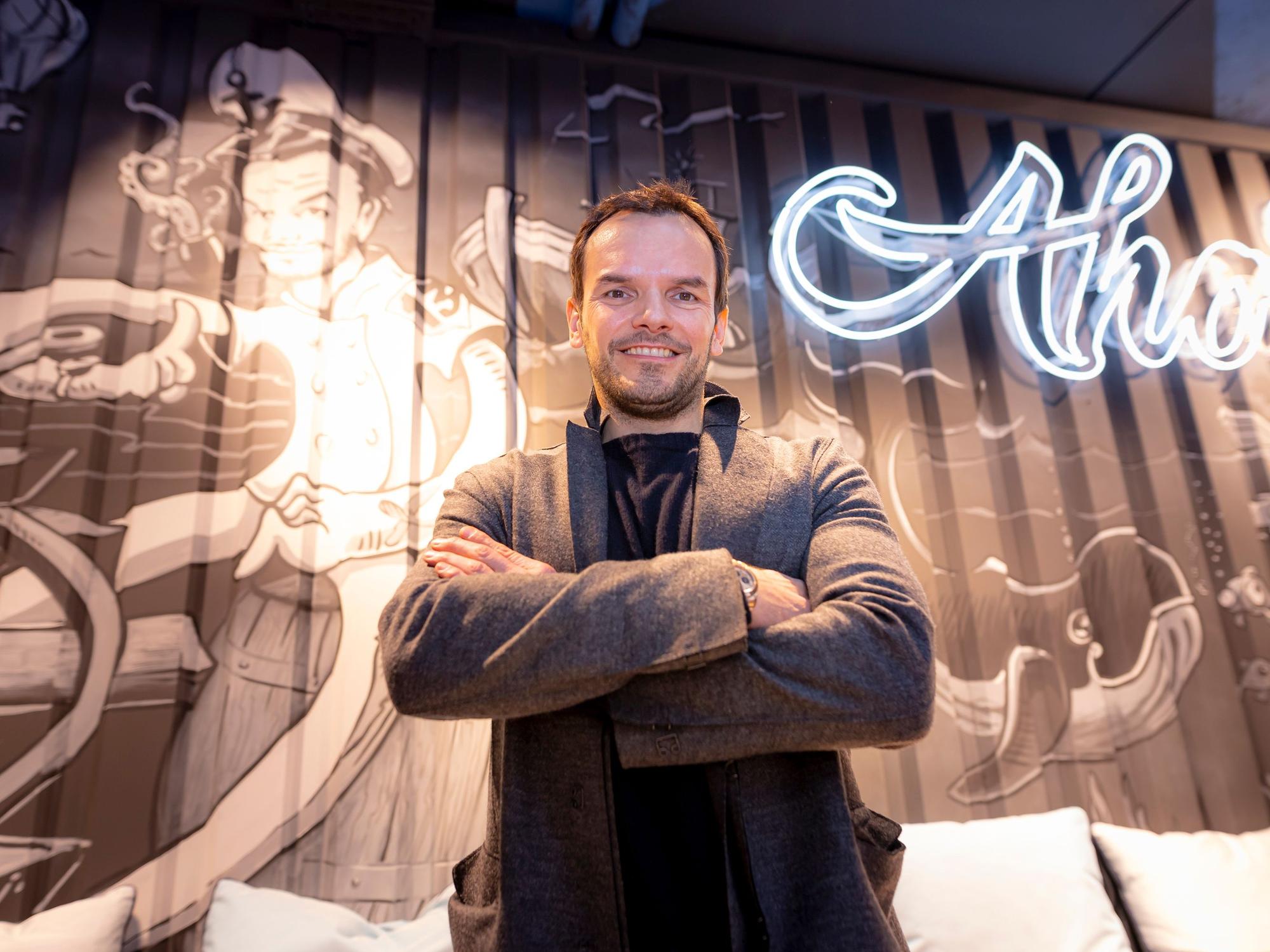 Steffen Henssler vor dem Logo seines Ahoi-Restaurants.