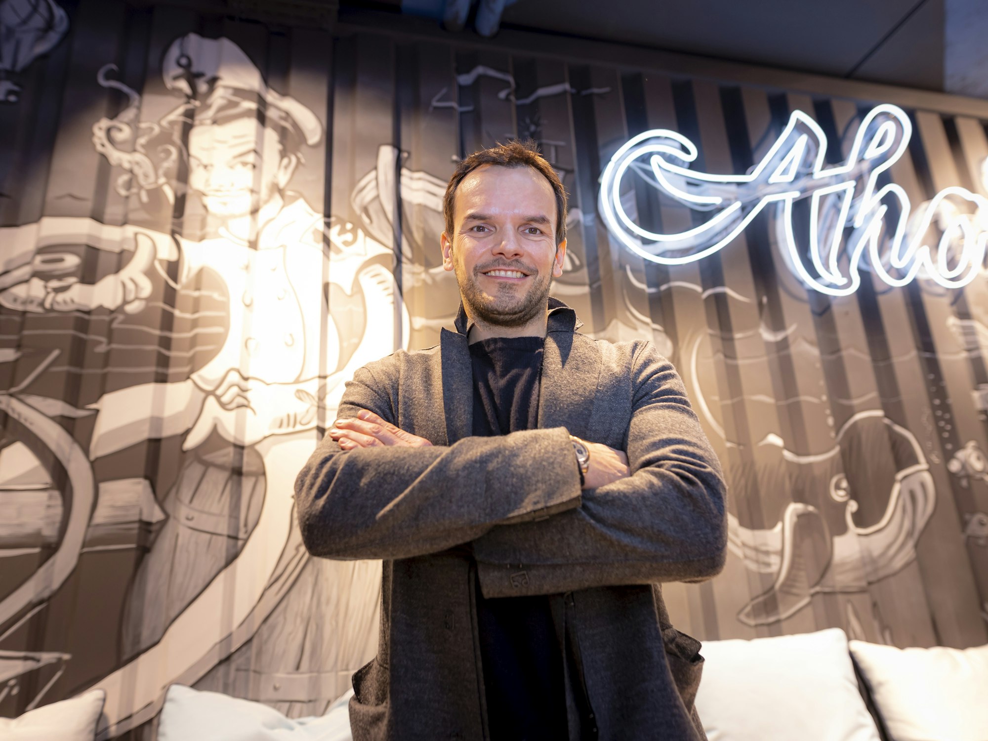Steffen Henssler vor dem Logo seines Ahoi-Restaurants.