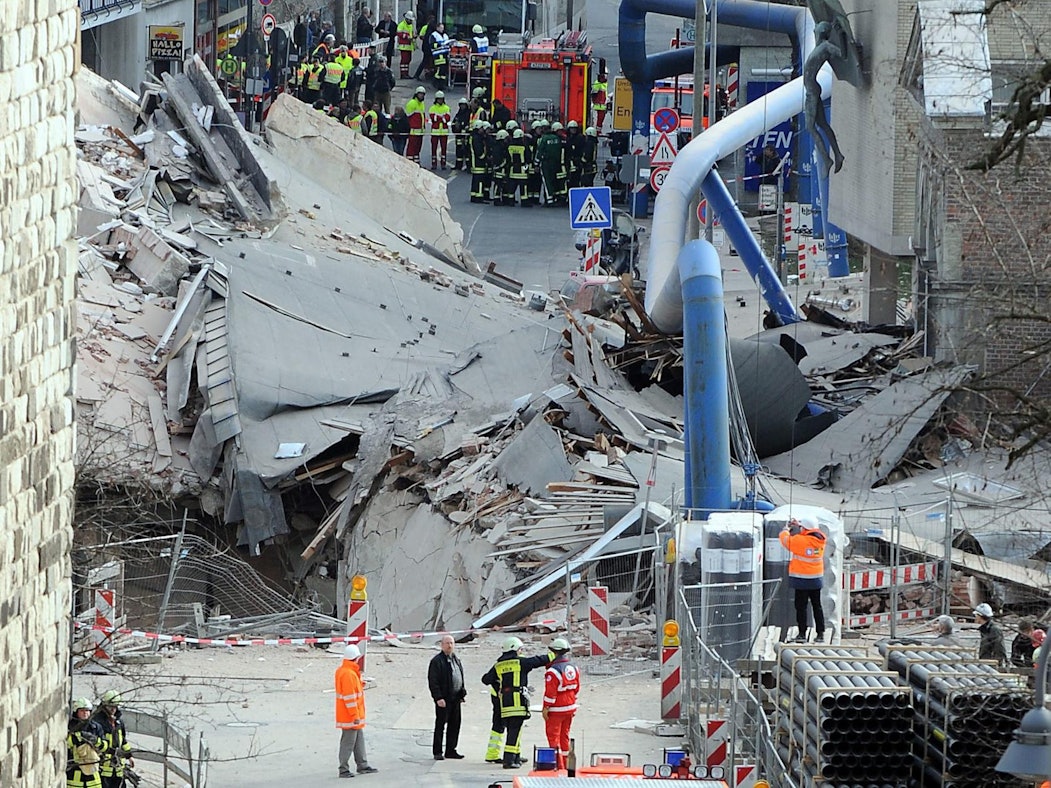 Zahlreiche Einsatzkräfte stehen vor den Trümmern des eingestürzten Stadtarchivs.