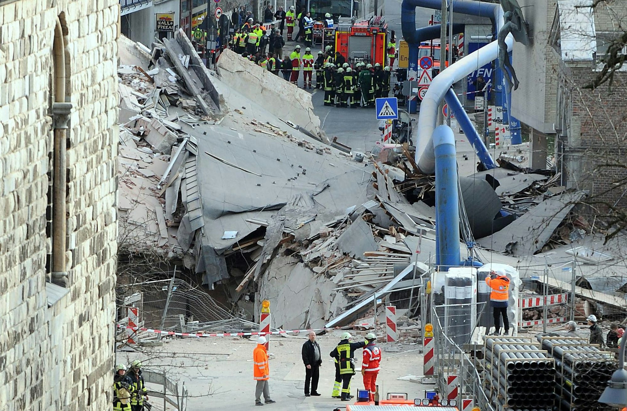 Zahlreiche Einsatzkräfte stehen vor den Trümmern des eingestürzten Stadtarchivs.