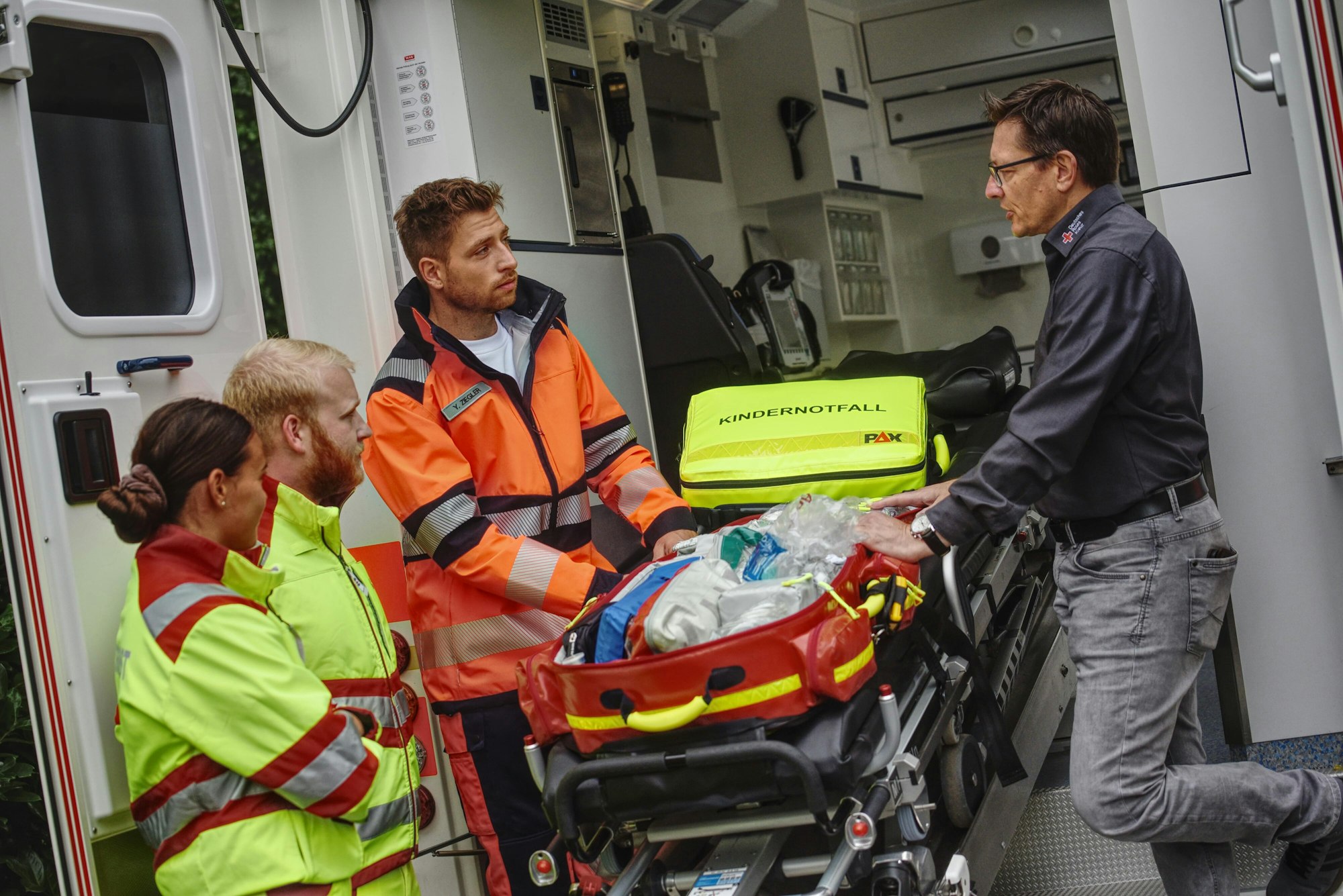 Mitarbeiter des DRK erklären Dominik Flade vor dem RTW den Rettungsrucksack.