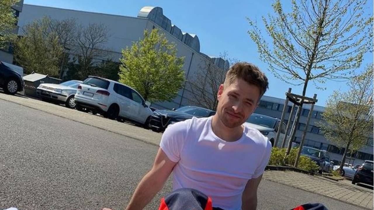 Dominik Flade sitzt in Arbeitskleidung eines Notfallsanitäters auf der Straße.