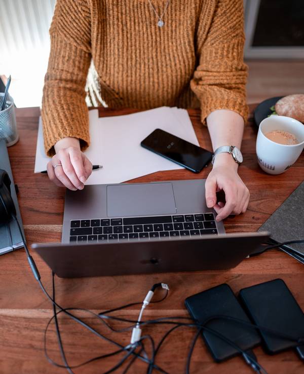 Eine Frau sitzt mit einem Laptop an einem Tisch im Homeoffice.