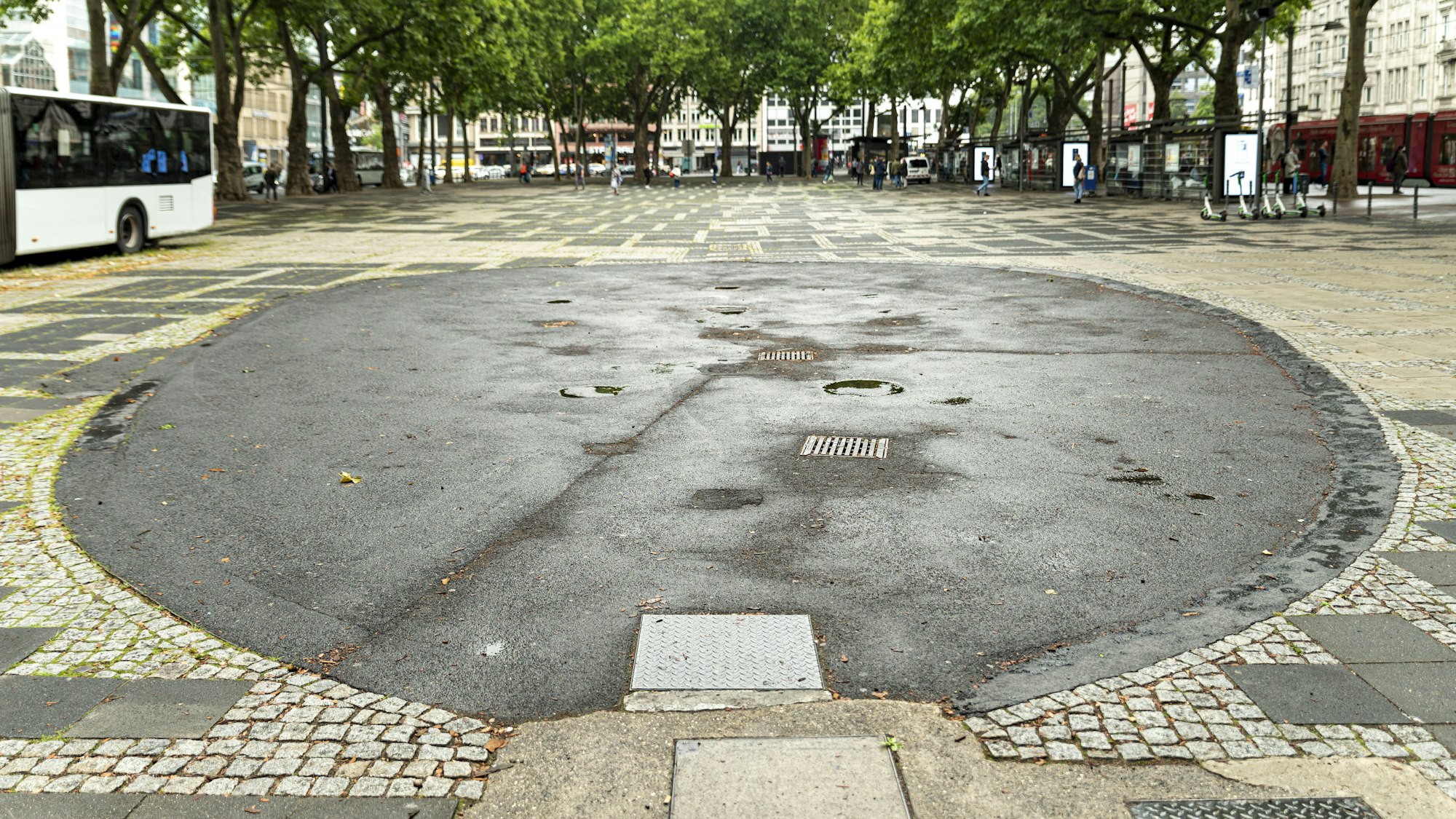 Ein Brunnen auf dem Neumarkt in Köln ist mit Bitumen verfüllt worden, so dass von ihm nur noch eine runde Fläche übrig ist.