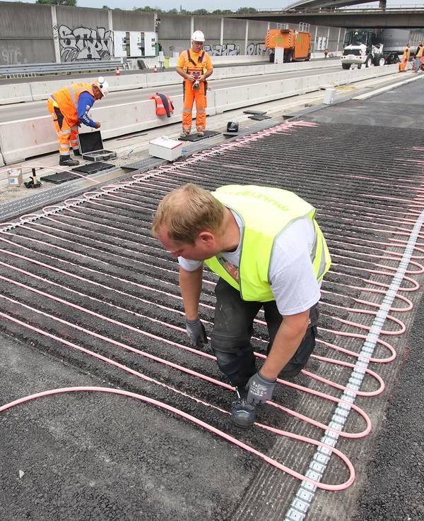 Ein Arbeiter bringt auf einem Testgelände neben der A3 Rohrleitungssysteme an.