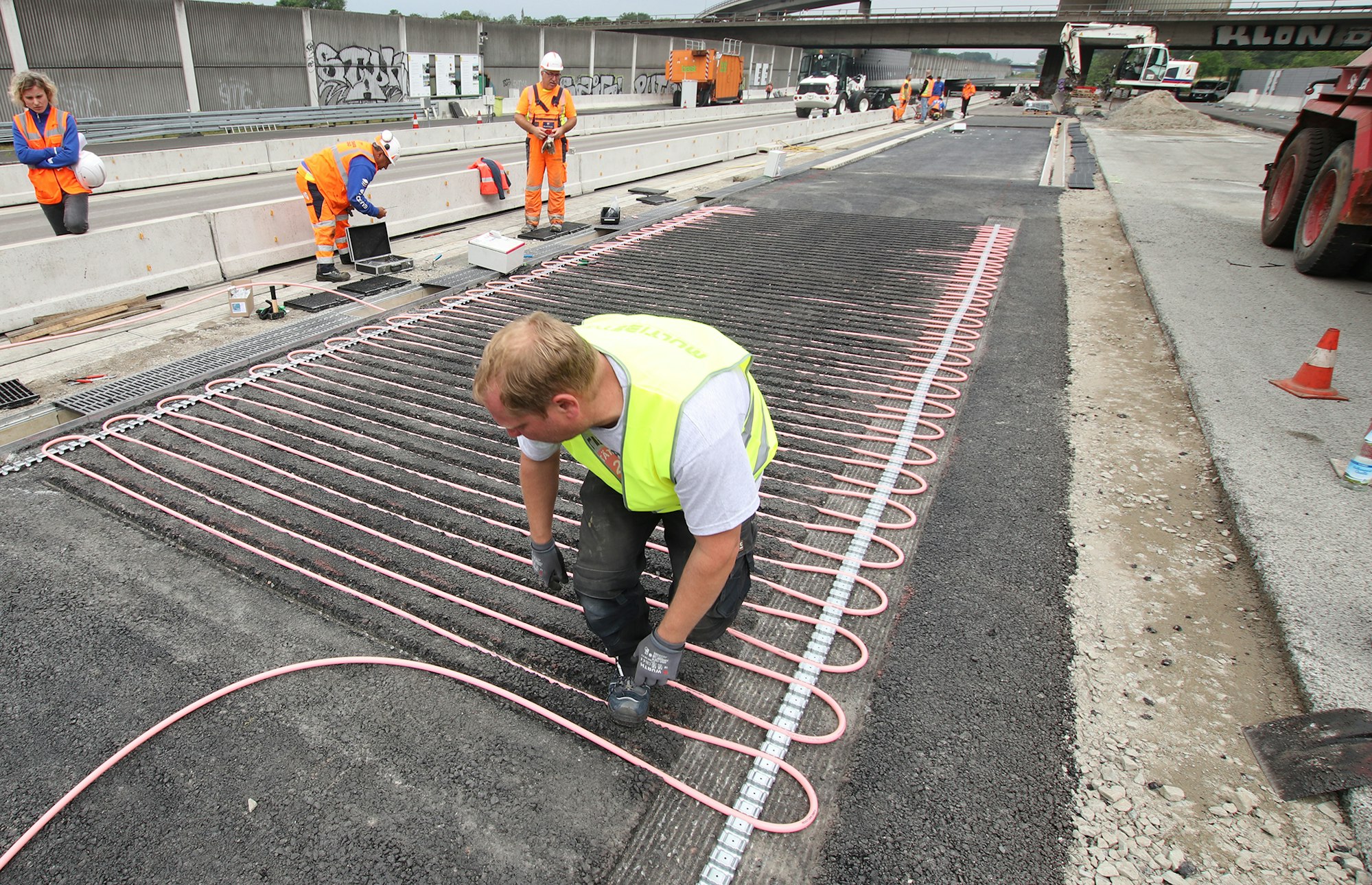 Ein Arbeiter bringt auf einem Testgelände neben der A3 Rohrleitungssysteme an.
