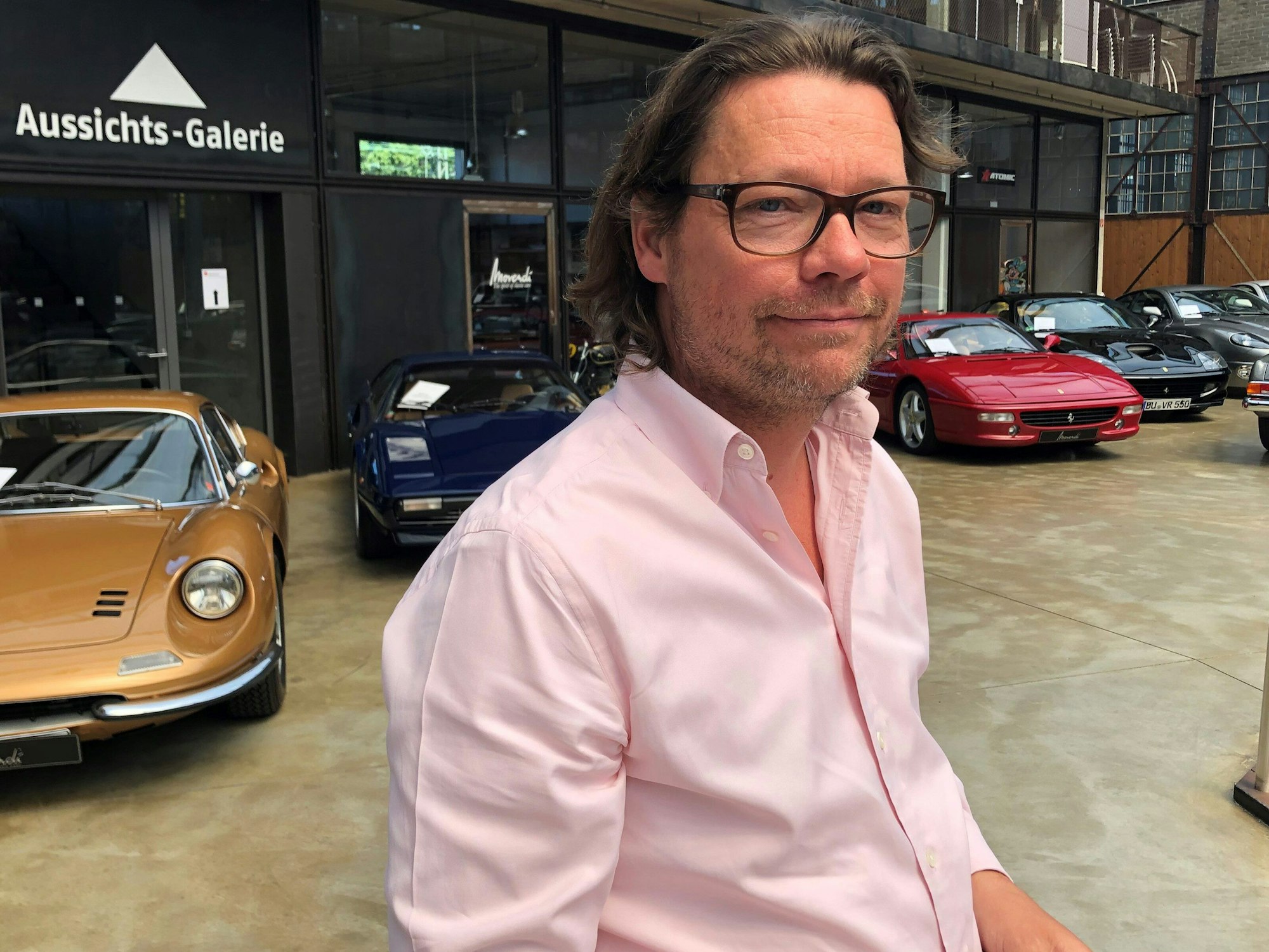 Bernhard Kerkloh, Inhaber und Geschäftsführer von Movendi in seinem Verkaufsraum, in dem zahlreiche Oldtimer stehen.