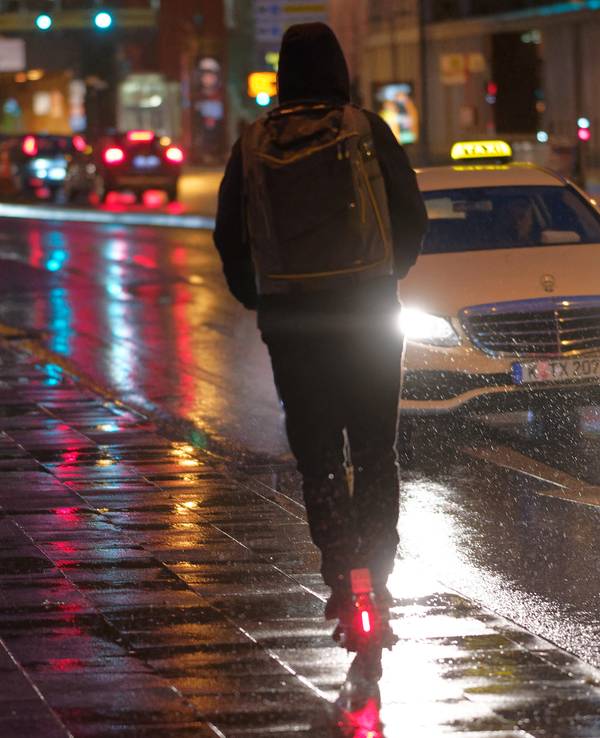 Ein Fahrer fährt auf einem E-Scooter bei Regenwetter durch die Kölner Innenstadt.