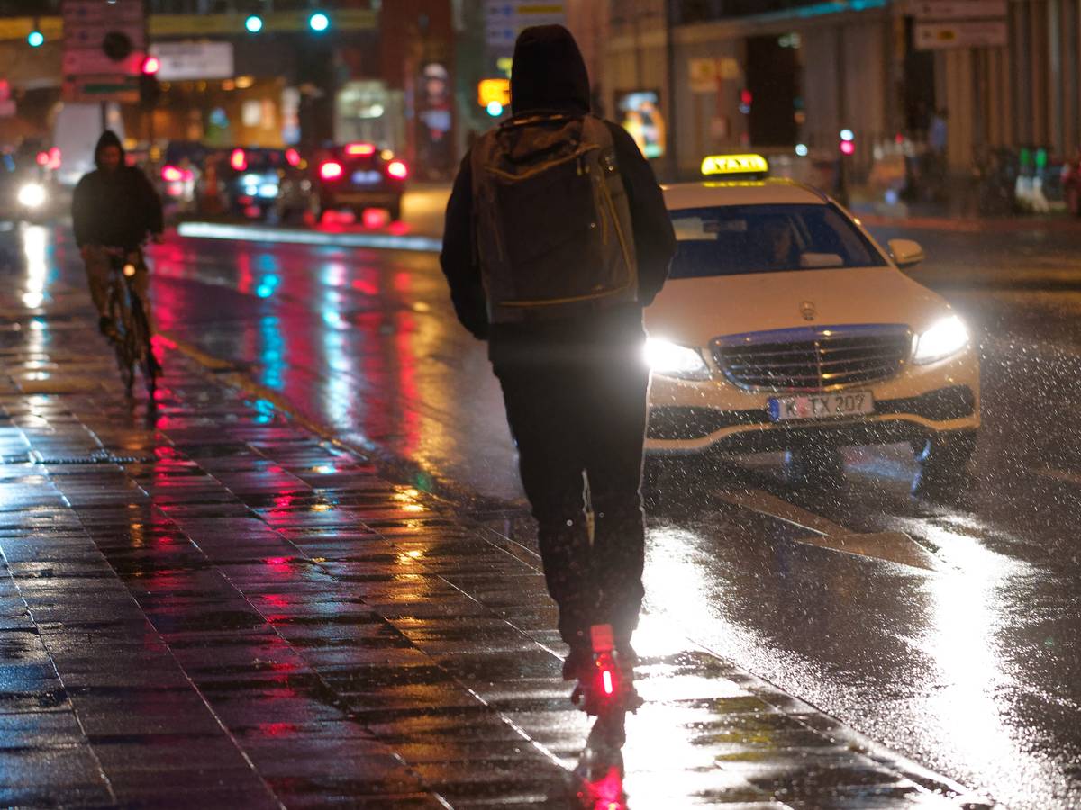 Ein Fahrer fährt auf einem E-Scooter bei Regenwetter durch die Kölner Innenstadt.