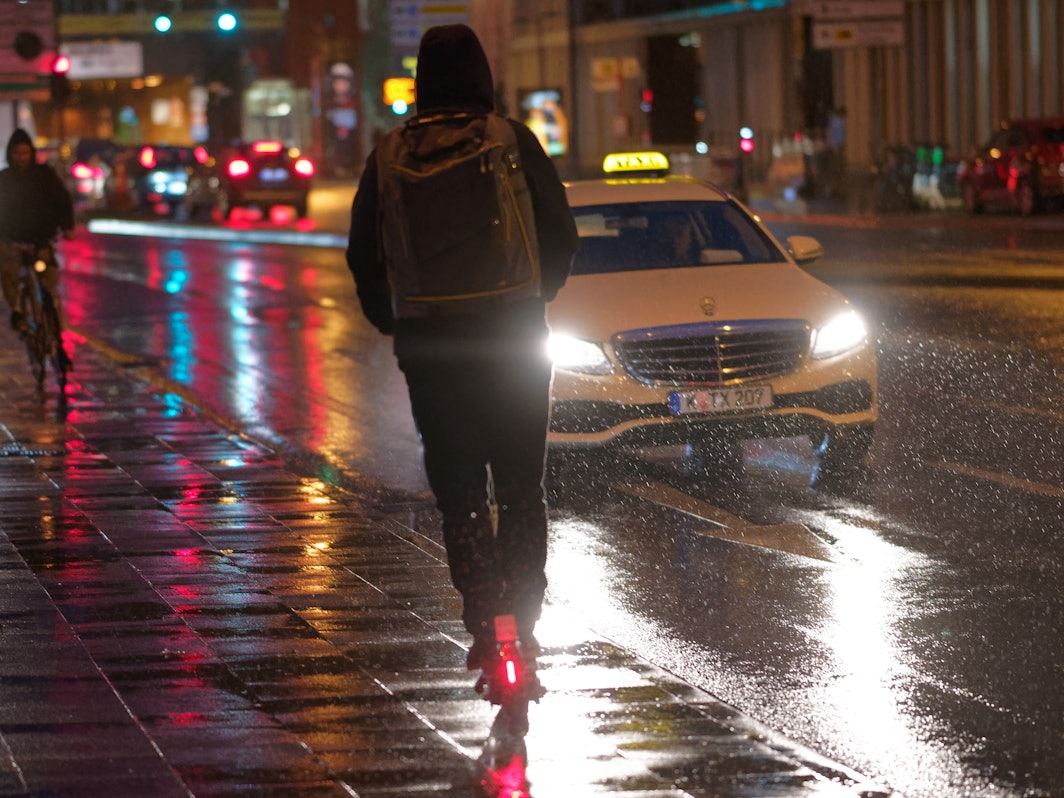 Ein Fahrer fährt auf einem E-Scooter bei Regenwetter durch die Kölner Innenstadt.