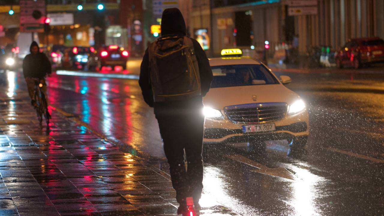 Ein Fahrer fährt auf einem E-Scooter bei Regenwetter durch die Kölner Innenstadt.