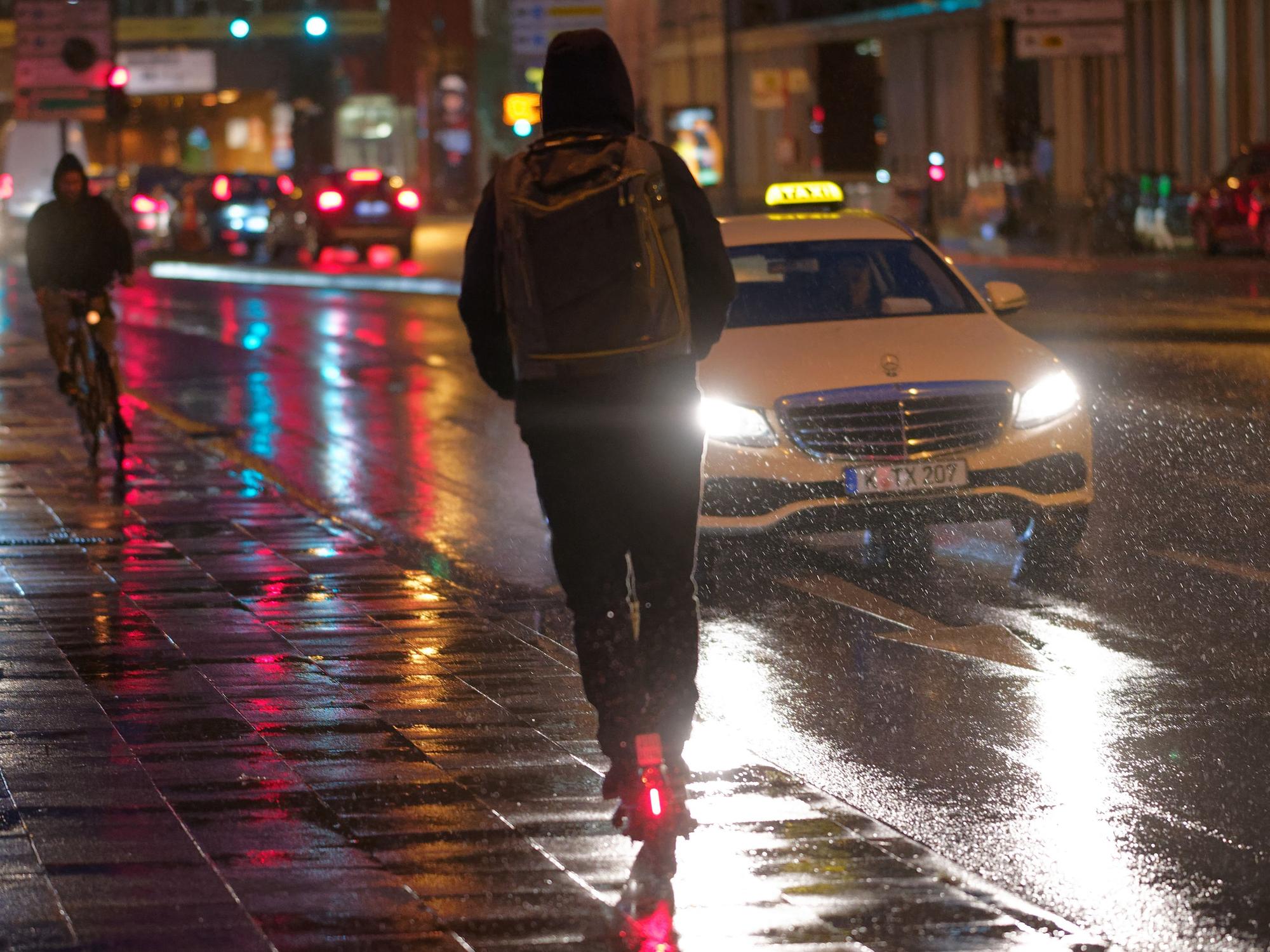 Ein Fahrer fährt auf einem E-Scooter bei Regenwetter durch die Kölner Innenstadt.