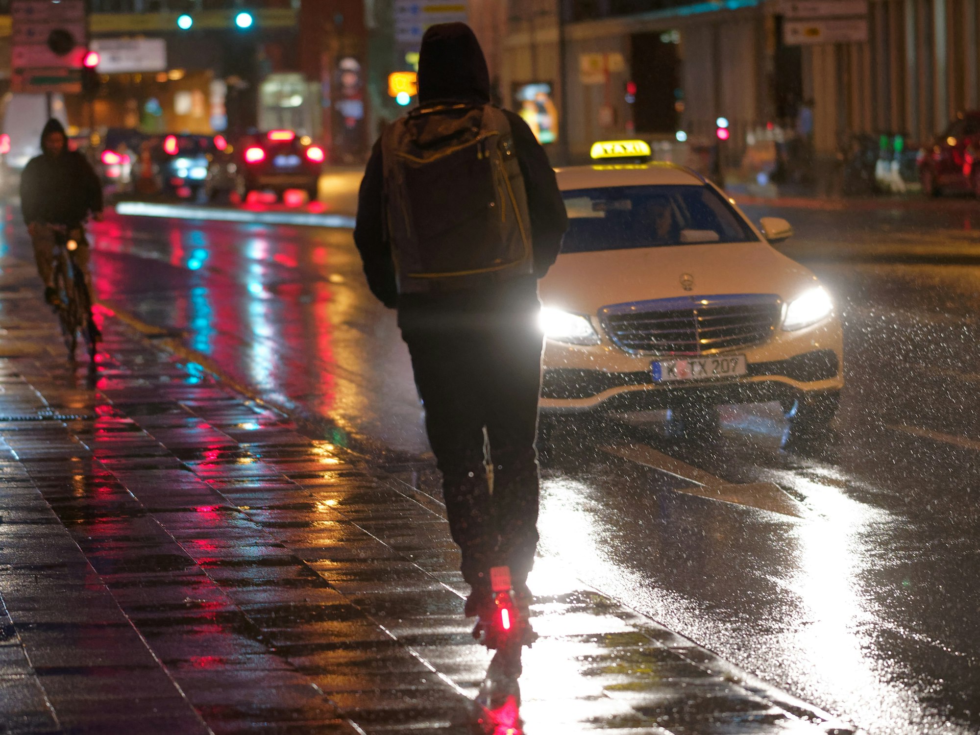 Ein Fahrer fährt auf einem E-Scooter bei Regenwetter durch die Kölner Innenstadt.