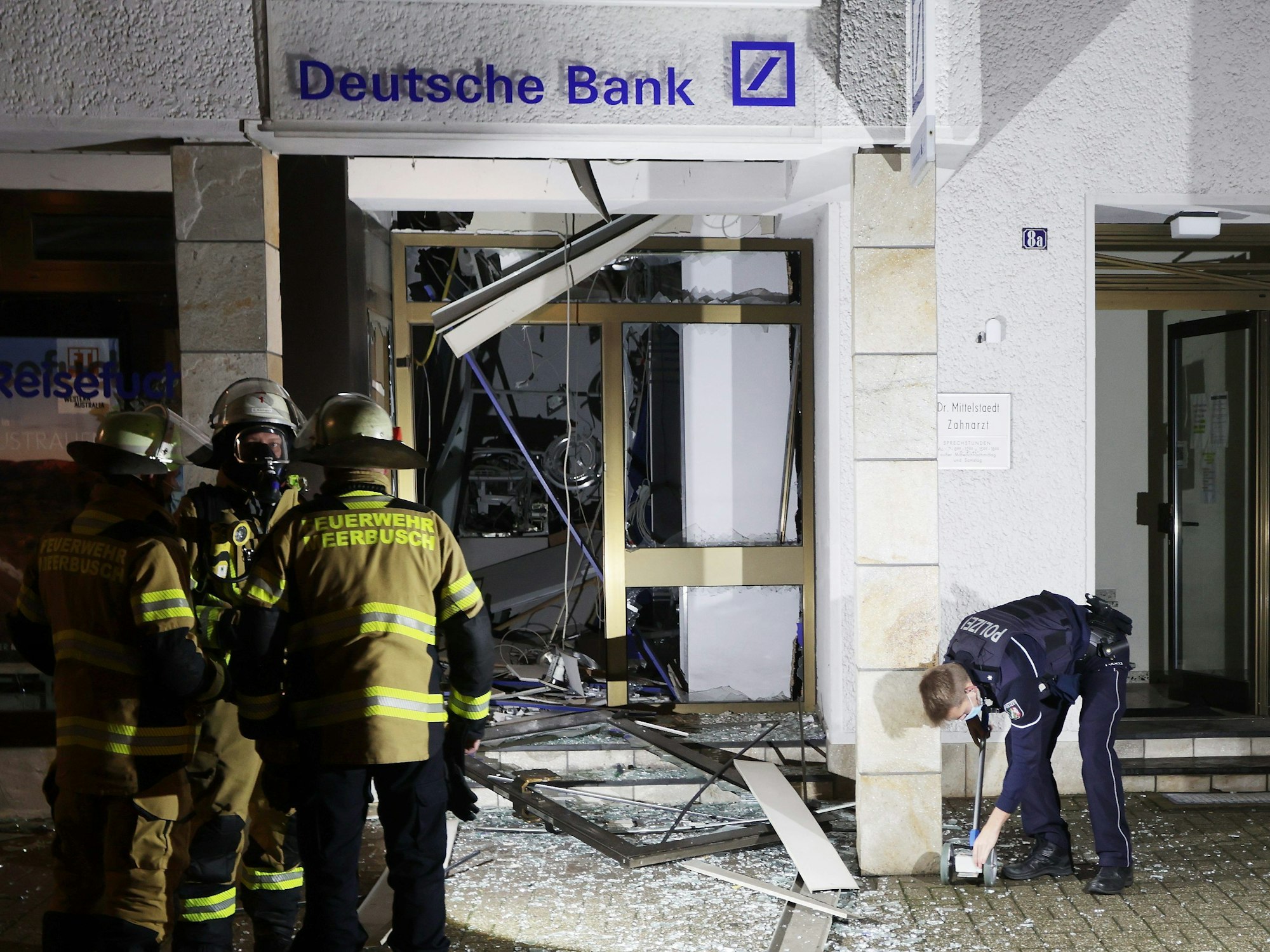 Feuerwehrleute stehen vor dem Selbstbedienungscenter der Deutschen Bank in Osterrath, in dem unbekannte Täter am 28. Dezember 2021 einen Geldautomaten gesprengt hatten.