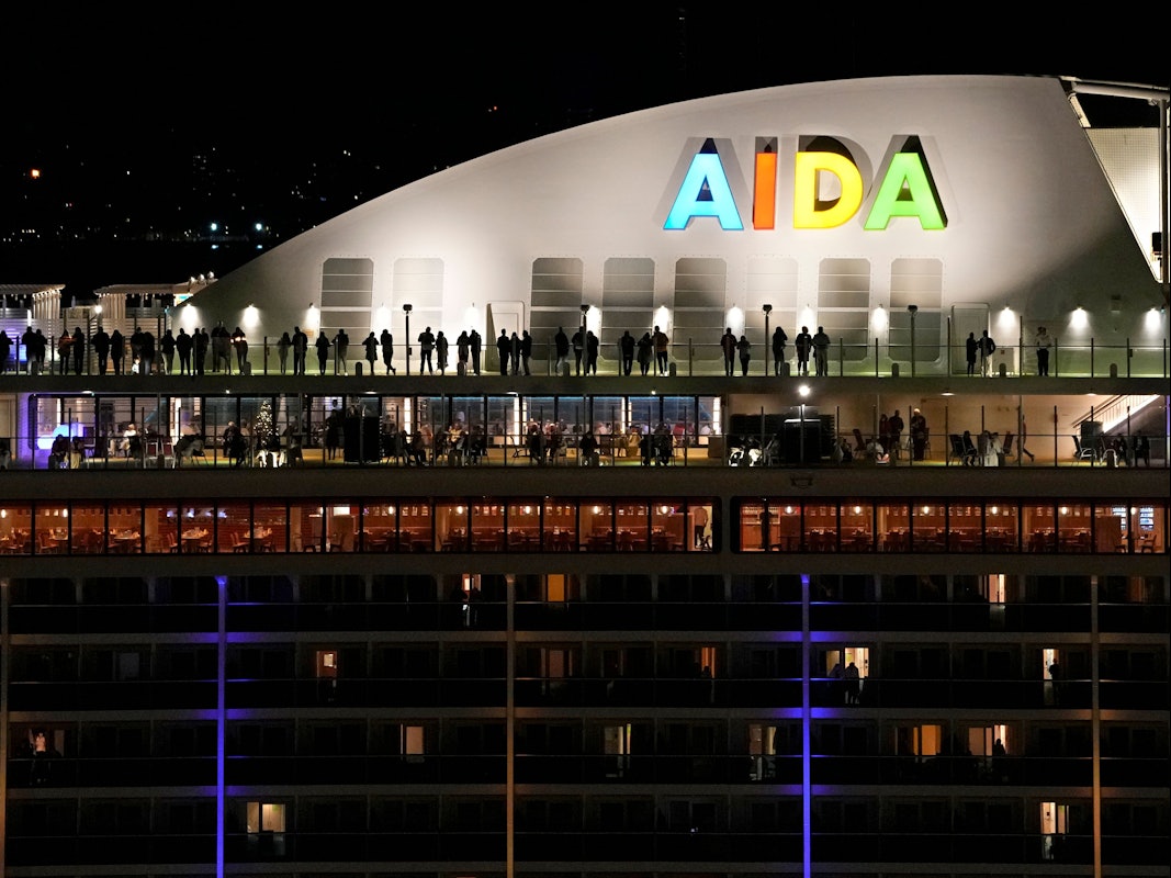 Menschen stehen auf dem Deck des deutschen Kreuzfahrtschiffs Aida Nova, das am Freitag kurz vor Mitternacht in Lissabon angelegt hat.