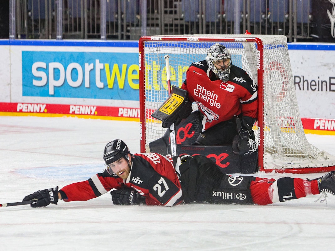 Pascal Zerressen liegt auf dem Eis, dahinter steht Justin Pogge im Tor