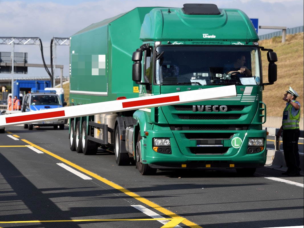 Ein Lkw steht an der Sperre der Leverkusener Brücke, sein Fahrer spricht mit einem Polizisten.