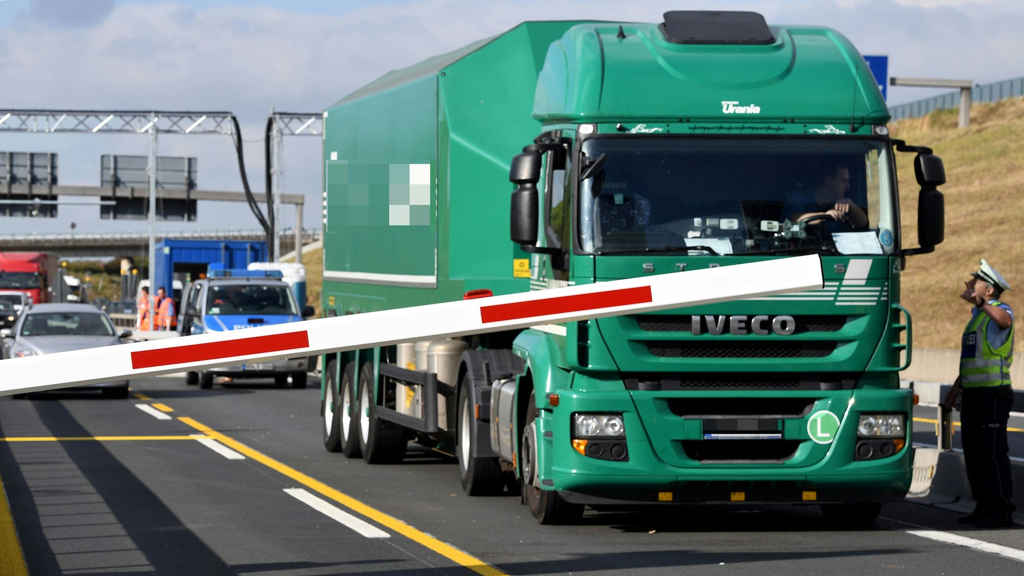 Ein Lkw steht an der Sperre der Leverkusener Brücke, sein Fahrer spricht mit einem Polizisten.