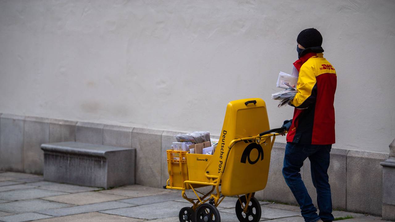 Ein DHL-Bote verteilt mit Mund-Nasen-Schutz Briefe.