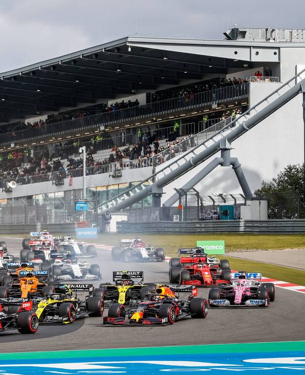 Max Verstappen fährt mit seinem Red Bull an der Spitze. Die Rennwagen der anderen Fahrer sind allesamt knapp dahinter. Im Hintergrund ist die Tribüne zu sehen.