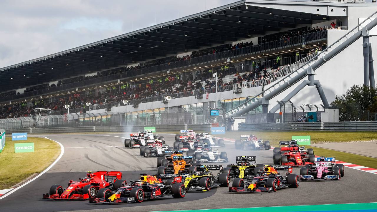 Max Verstappen fährt mit seinem Red Bull an der Spitze. Die Rennwagen der anderen Fahrer sind allesamt knapp dahinter. Im Hintergrund ist die Tribüne zu sehen.