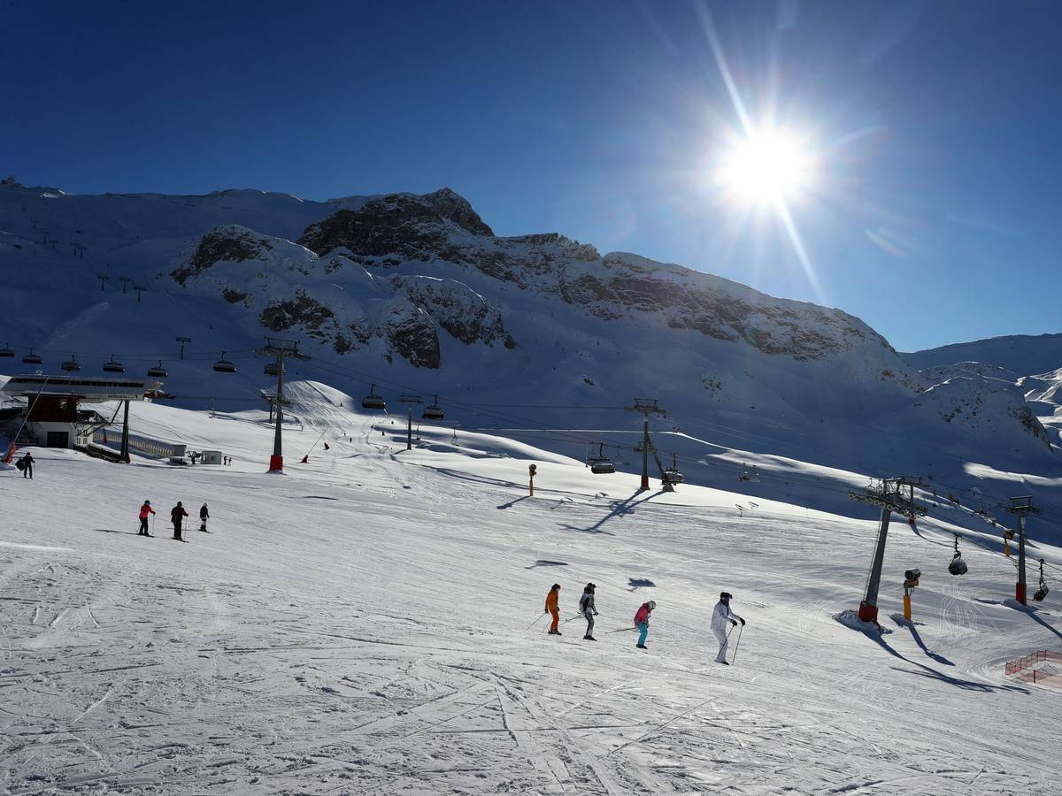 Mehrere Skifahrer fahren eine schneebedeckte Piste herab.