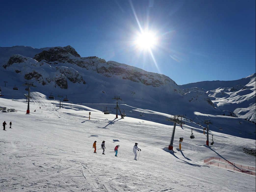 Mehrere Skifahrer fahren eine schneebedeckte Piste herab.