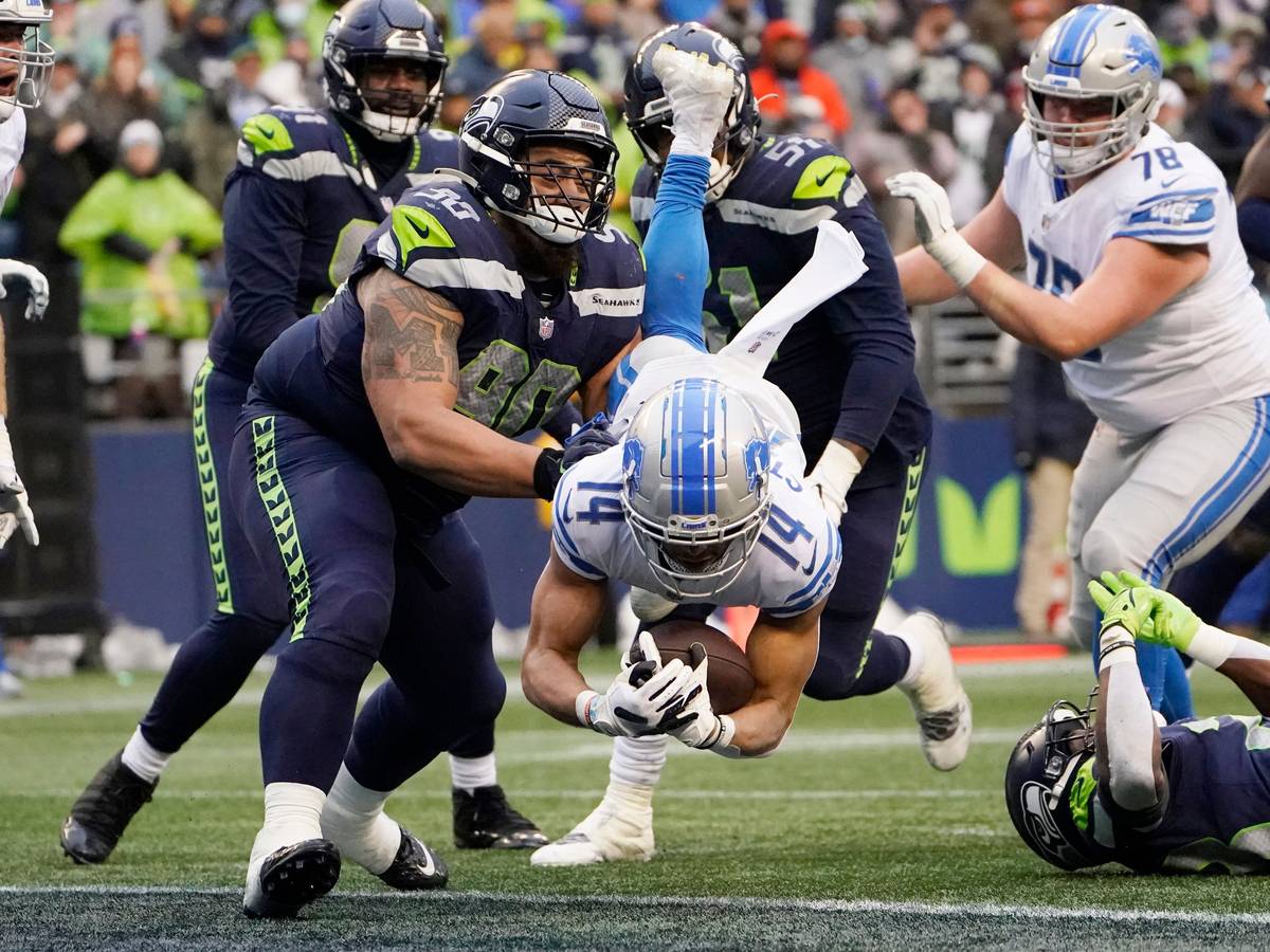 Amon-Ra St. Brown springt mit dem Football im Arm über die Touchdown-Linie.
