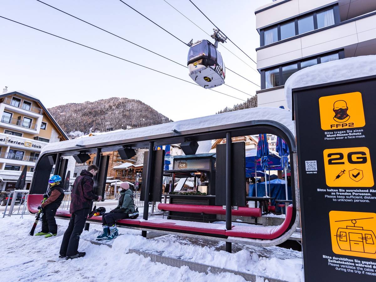 Skifahrer warten im Skigebiet bei der Gondel, wo Schilder auf die Corona-Regelungen hinweisen. +++ dpa-Bildfunk +++
