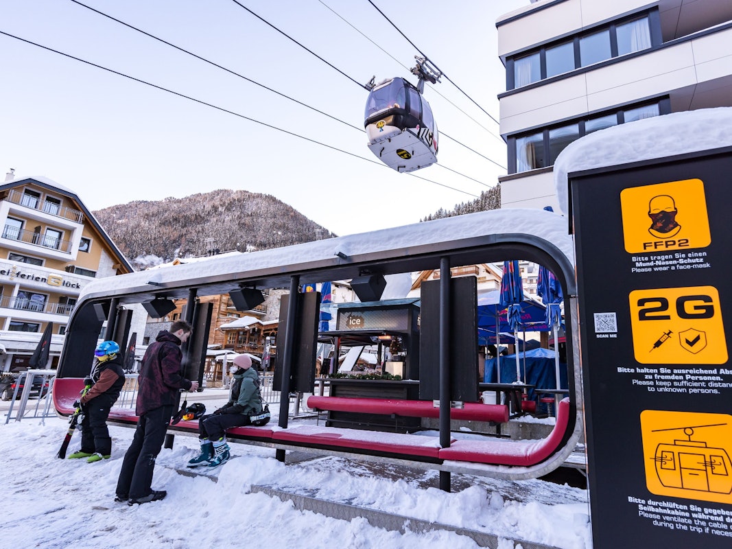 Skifahrer warten im Skigebiet bei der Gondel, wo Schilder auf die Corona-Regelungen hinweisen. +++ dpa-Bildfunk +++