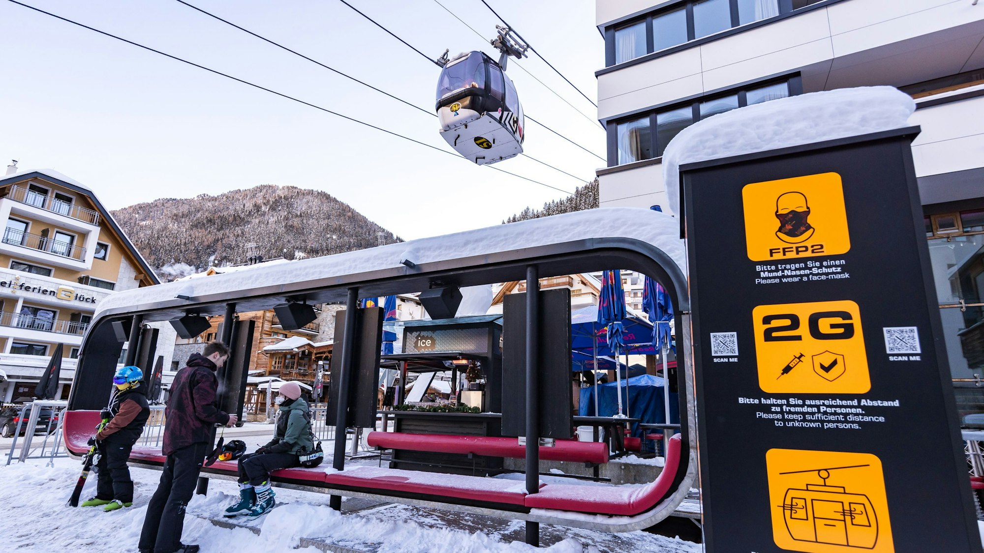 Skifahrer warten im Skigebiet bei der Gondel, wo Schilder auf die Corona-Regelungen hinweisen. +++ dpa-Bildfunk +++
