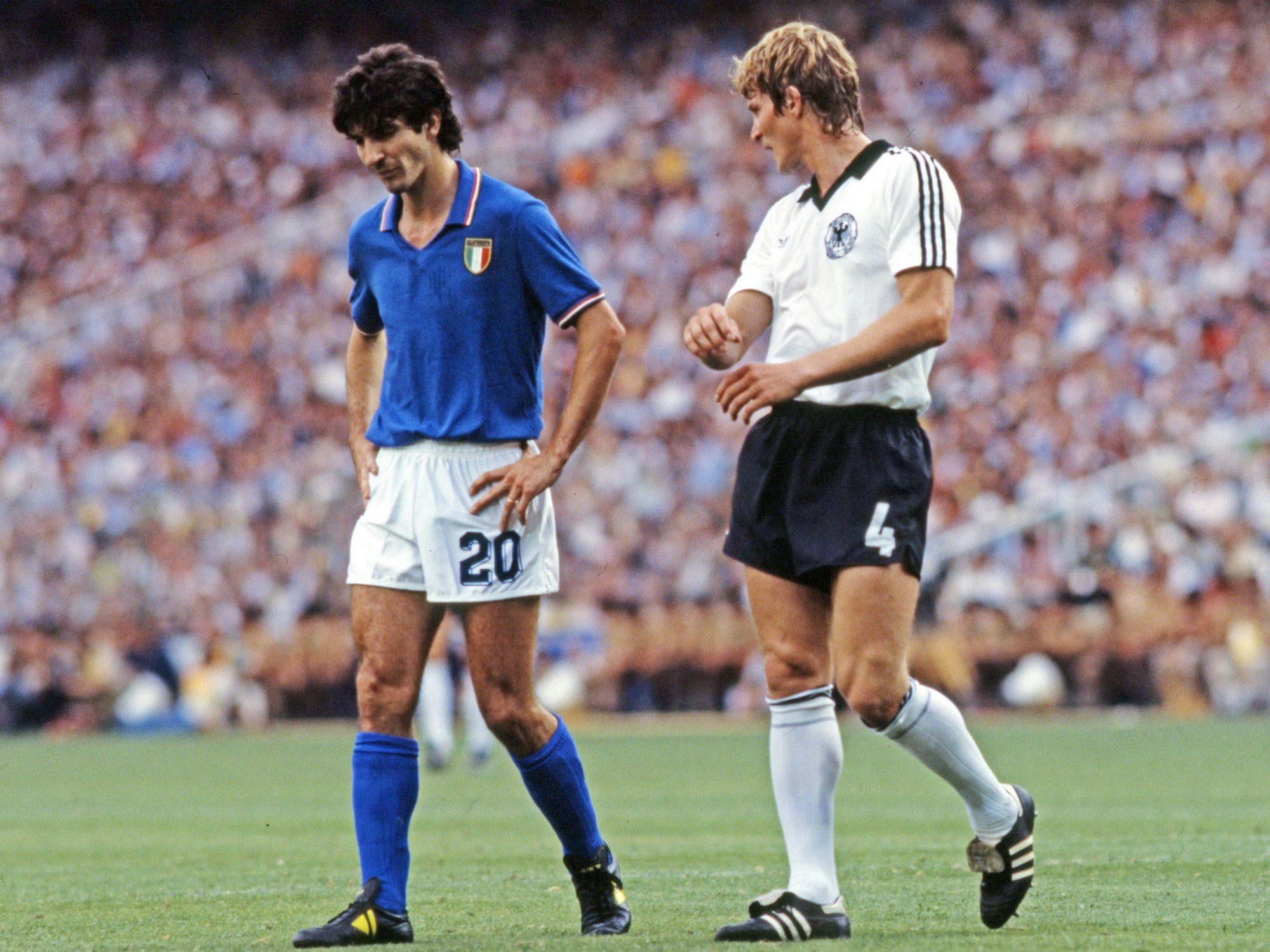 Paolo Rossi hat den Kopf gesenkt und die Hände in den Hüften, Karlheinz Förster geht neben ihm.