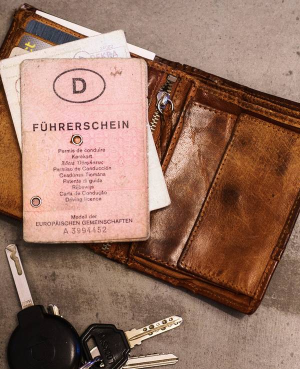 Ein rosa Führerschein, ein Autoschlüssel, eine Geldbörse und ein Fahrzeugschein liegen auf dem Tisch. Bis 2033 müssen Millionen von Führerscheinen umgetauscht werden, damit sie fälschungssicherer sind.