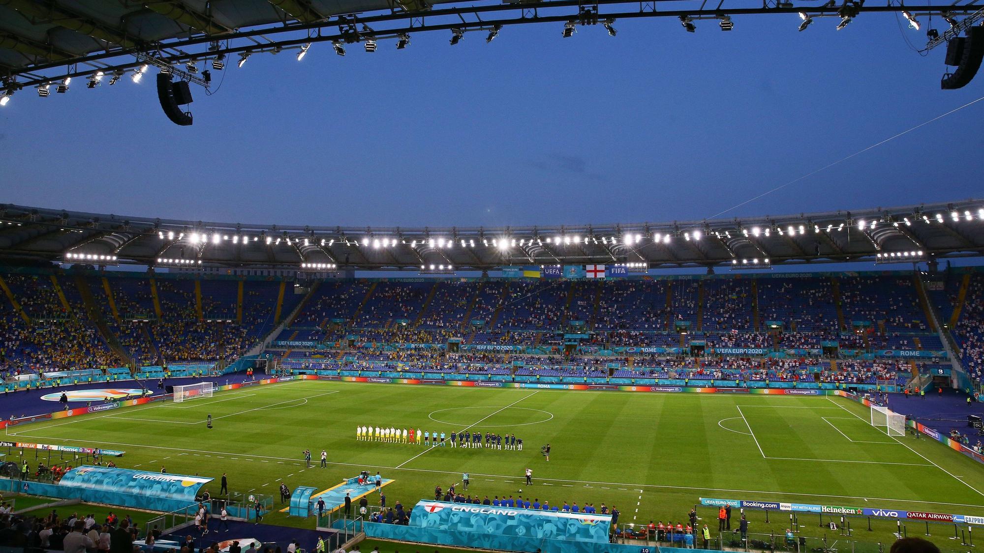 Das Stadioninnere ist aus dem Weitwinkel zu sehen. Die Mannschaft stehen auf dem Platz und lauschen den Nationalhymnen.