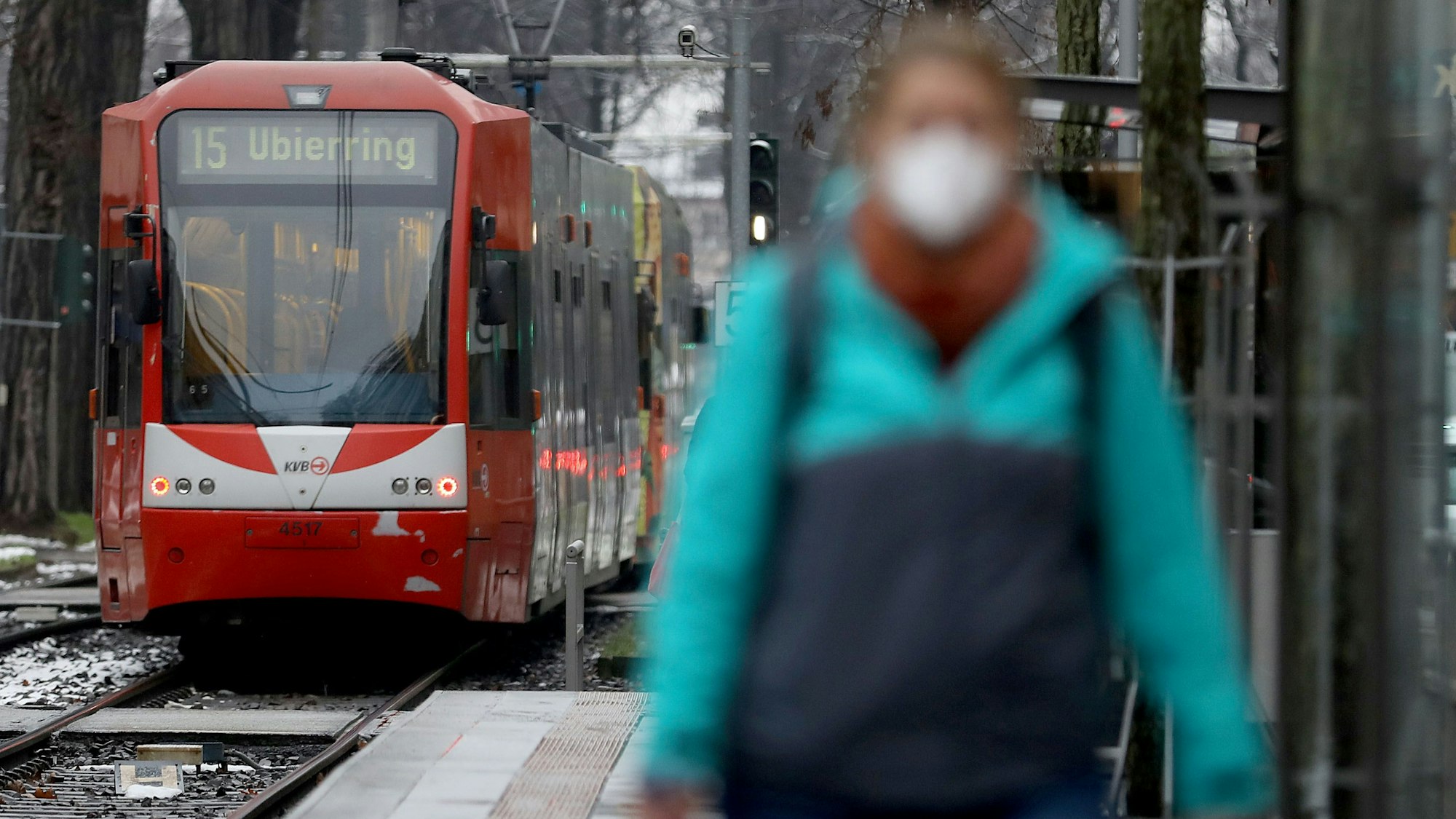 Eine Frau geht in Köln mit einer Maske an einem Bahnsteig entlang.
