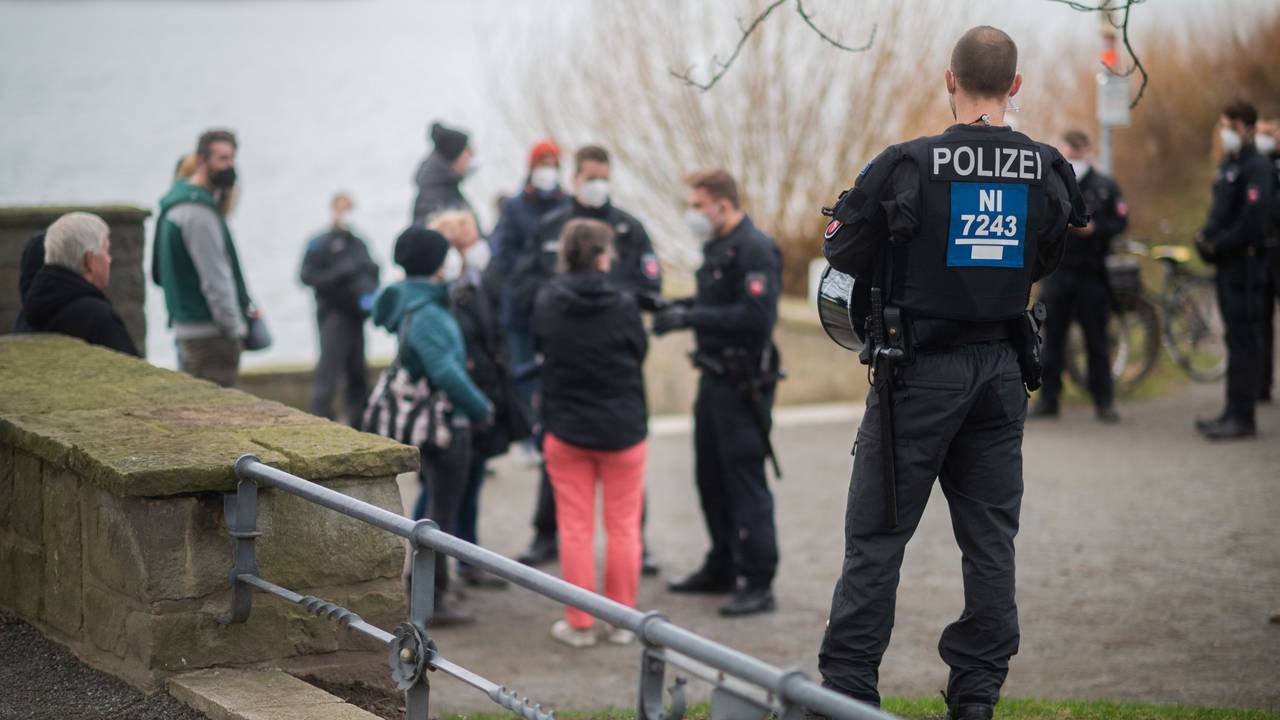 Polizisten stehen vor einer Menschengruppe an der Löwenbastion am Maschsee. Die Polizei Hannover hat einen sogenannten „Corona-Spaziergang“ - eine unangemeldete Veranstaltung mit mehreren Personen als Protest gegen die staatlichen Corona-Maßnahmen - kurzerhand als unangemeldete Demonstration bewertet. Das Symbolbild wurde am zweiten Januar 2022 aufgenommen.