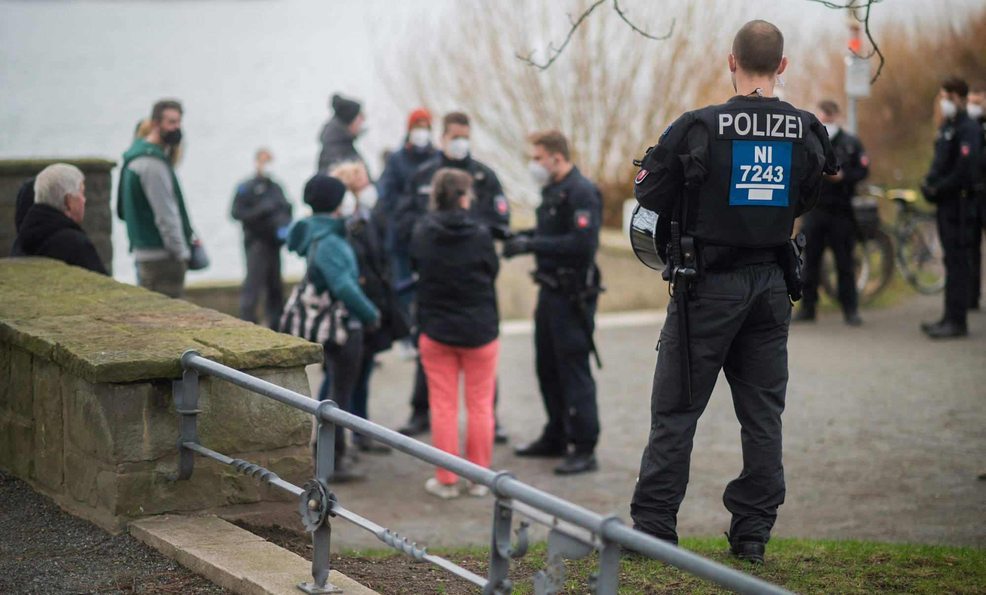 Polizisten stehen vor einer Menschengruppe an der Löwenbastion am Maschsee. Die Polizei Hannover hat einen sogenannten „Corona-Spaziergang“ - eine unangemeldete Veranstaltung mit mehreren Personen als Protest gegen die staatlichen Corona-Maßnahmen - kurzerhand als unangemeldete Demonstration bewertet. Das Symbolbild wurde am zweiten Januar 2022 aufgenommen.