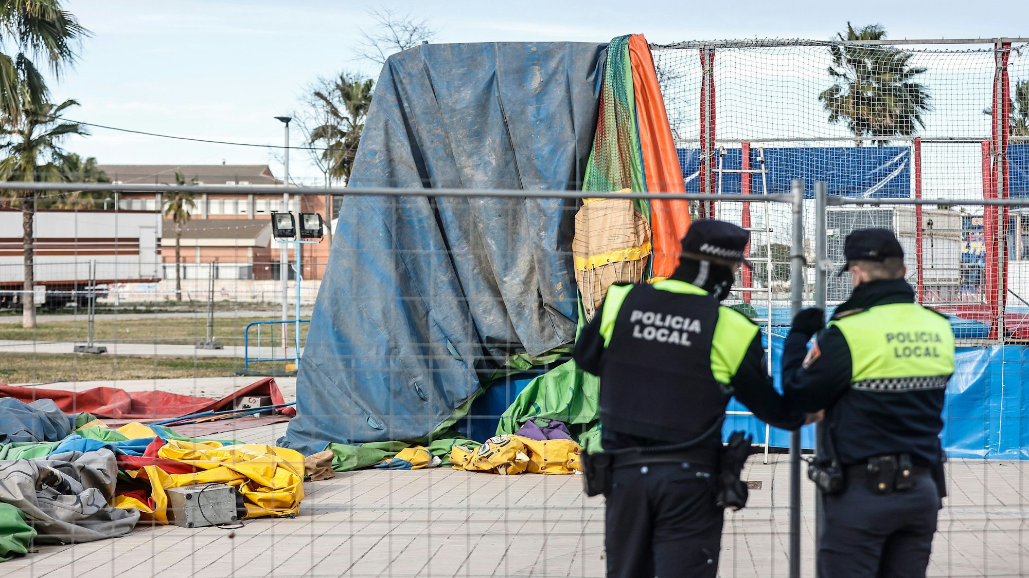 Zu sehen ist die kaputte Hüpfburg, vor ihr stehen zwei spanische Polizisten.