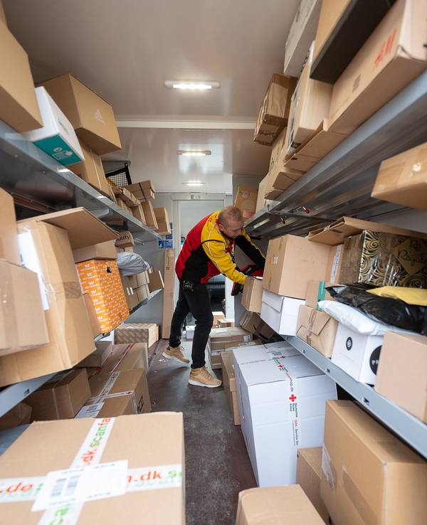 Ein DHL-Mitarbeiter sortiert in seinem Transporter die Pakete und Päckchen für die nächsten Zustellungen. (Zu dpa "Zusteller tragen vor Weihnachten Millionen Päckchen aus")