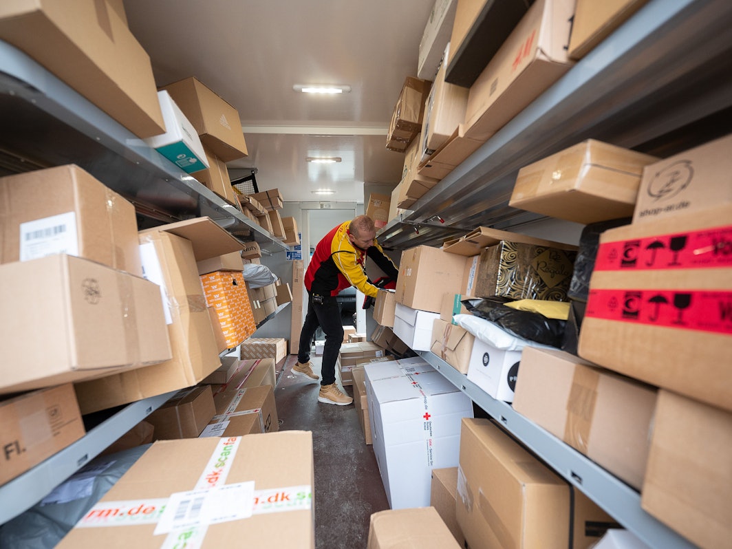 Ein DHL-Mitarbeiter sortiert in seinem Transporter die Pakete und Päckchen für die nächsten Zustellungen. (Zu dpa "Zusteller tragen vor Weihnachten Millionen Päckchen aus")
