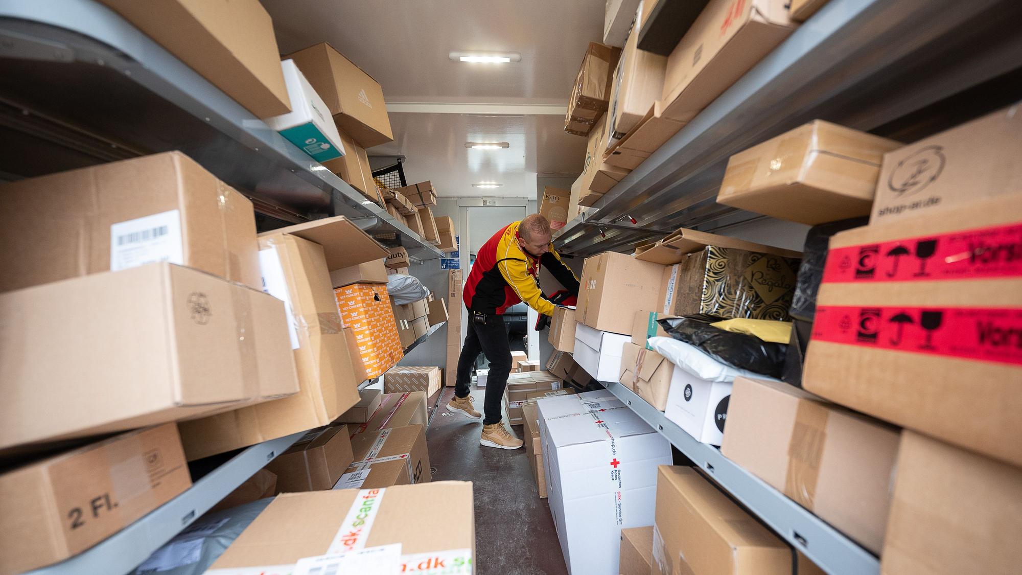 Ein DHL-Mitarbeiter sortiert in seinem Transporter die Pakete und Päckchen für die nächsten Zustellungen. (Zu dpa "Zusteller tragen vor Weihnachten Millionen Päckchen aus")