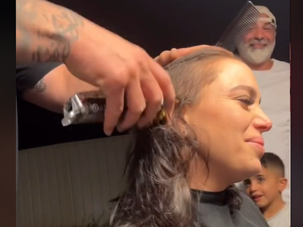 Mann rasiert den Kopf einer Frau, die das Gesicht verzehrt.